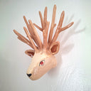 Ceramic sculpture of a deer head with many, many antlers and a red eye. 