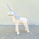 Unicorn ceramic sculpture with a light gray horn and mane on a concrete surface.