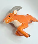 Glazed ceramic sculpture of an orange elk character, bounding forward with long front legs and short back legs. They have long gray horns.