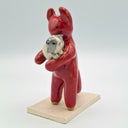 Red ceramic sculpture of a devil character, standing with guinea pigs.