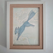 Framed artwork of a blue fox like animal bounding through the sky with cloud background