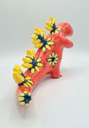 Red ceramic figurine of a kaiju monster akin to a dinosaur, with a very long tail and spikes down its back with floral patterns on a white background