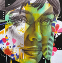 Graphite illustration of a woman's face, close up with bright colorful accent coloring. She has feathers and flowers around her face.