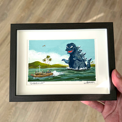 Framed illustration of Godzilla emerging from water with a boat and palm trees in the background.