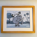 Framed cartoon illustration of two characters riding an elephant on a bike with palm trees in the background.