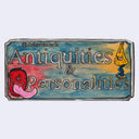 A rectangular hand-painted wooden sign with distressed edges, featuring text in raised lettering. The background is a mottled mix of blue, green, yellow, and pink, decorated with a red cartoonish lamp yokai and a yellow smiling figure on the right.