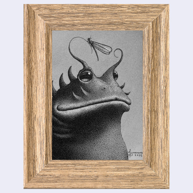 Framed artwork of a frog like creature with a dragonfly on its head against a gray background