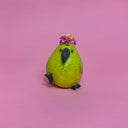 Small ceramic figure of a rounded, chubby green bird with flowers coming out the top of its head.
