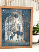 Paper cut illustration of deer and its doe, standing amongst trees with a tree growing out of their backs.