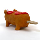 Sculpture of a corn dog, designed to look like a dog with a cute, silly face and a metallic unicorn horn atop its head. It has a squiggle of ketchup on its back.