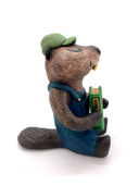 Sculpture of a beaver, dressed like a person in overalls and a green hat. It sits and holds Henry David Thoreau's "Walden"