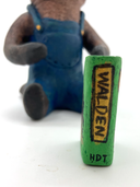 Sculpture of a beaver, dressed like a person in overalls and a green hat. It sits and holds Henry David Thoreau's "Walden"