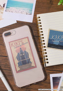 2 stickers using art from Kiki's Delivery Service in a retro style, the first is of Jiji in a wrapped wicker bird's cage and the other is of Kiki and Jiji sitting atop a roof looking out at the city. Stuck on a phone and on a notebook.