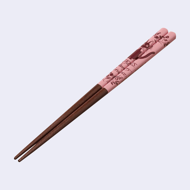 Pair of dark grain wooden chopsticks with the top half is pink with illustrations of flowers and Jiji from Kiki's Delivery Service.