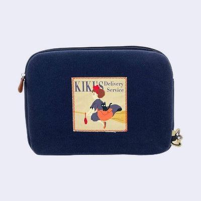 Navy blue zippered pouch with a sewn on patch featuring artwork of Kiki from Kiki's Delivery Service riding on her broom with her cat Jiji, a crossbody bag and a small red radio.