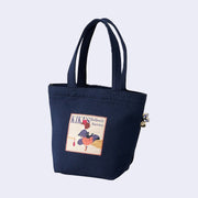 Navy blue tote bag with a sewn on patch of Kiki from Kiki's Delivery Service riding on her broom with her cat Jiji, a crossbody bag and a small red radio.