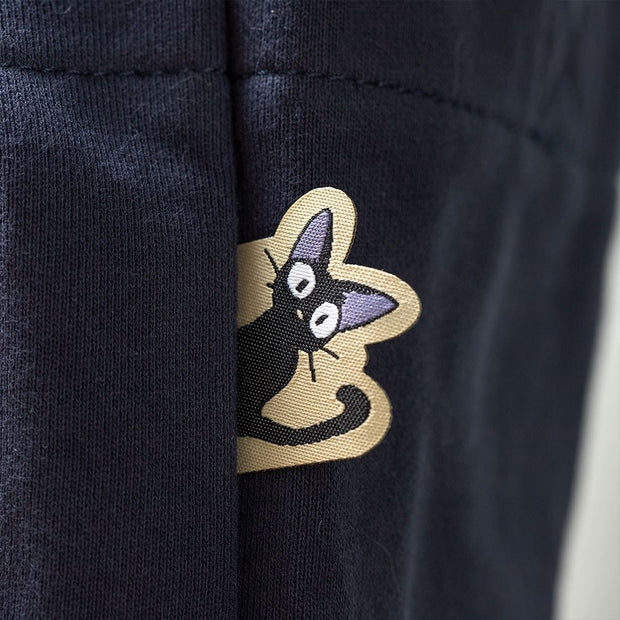 Close up of tag attached to bag, a die cut embroidery of Jiji the cat sticking its head out.