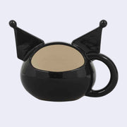 Ceramic mug of Kuromi's head, with her pointed ears sculpted off of the mug. A handle comes off the side of her head. Back view shows opening where it is sipped out of.