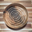 Wooden bowl with concentric circle pattern on a wooden surface