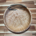 Wooden tray with engraved design of a cute cartoon child with horns and a fang on a wooden surface