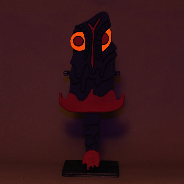 Sculpture of a stylized paddle or sword, modeled to look like Hedorah ink dark gray, orange and red colorings.l