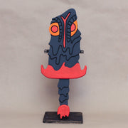 Sculpture of a stylized paddle or sword, modeled to look like Hedorah ink dark gray, orange and red colorings.l