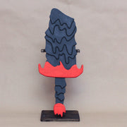 Sculpture of a stylized paddle or sword, modeled to look like Hedorah in dark gray, orange and red colorings.