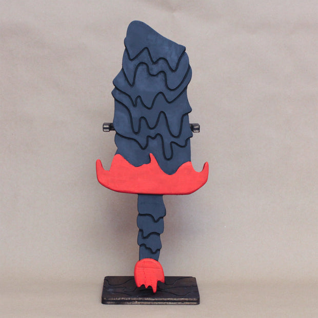Sculpture of a stylized paddle or sword, modeled to look like Hedorah in dark gray, orange and red colorings.