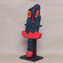 Sculpture of a stylized paddle or sword, modeled to look like Hedorah in dark gray, orange and red colorings.