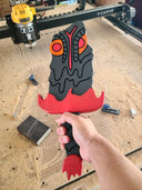 Sculpture of a stylized paddle or sword, modeled to look like Hedorah in dark gray, orange and red colorings. A hand holds the sculpture from the handle.