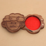 Die cut wooden box of a small, cute child's head with 2 horns and a tiny fang. Lid slides off to reveal a red felt liner.