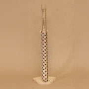 Wooden bat with black metal bumps evenly atop the surface, on a beige background