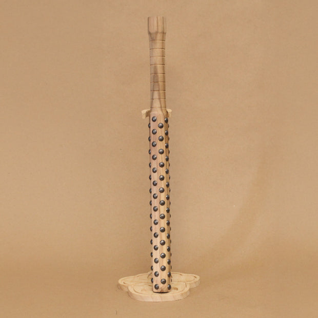 Wooden bat with black metal bumps evenly atop the surface, on a beige background