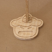 Close up of a wooden base shaped like a cartoon demon head, with a cute open mouth expression