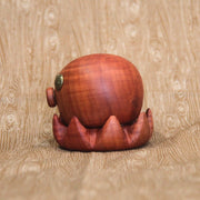 Wooden sculpture of a small octopus, with shiny metal eyes and an "o" shaped mouth. Its tentacles curl up towards itself.