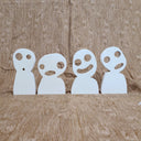 Wooden die cut sculpture of Kodamas, white ghost spirits from Princess Mononoke with circular eyes and open smiles or mouth expressions. They stand side by side, 4 in total.