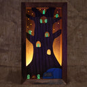 Wooden sculpture contained in a back lit box of a tree, with many small cute ghostly characters (kodamas) peeking out. 