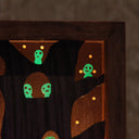 Wooden sculpture contained in a back lit box of a tree, with many small cute ghostly characters (kodamas) peeking out. 