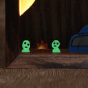 Wooden sculpture contained in a back lit box of a tree, with many small cute ghostly characters (kodamas) peeking out. 