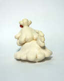 A small cream-colored ceramic figurine of a cute poodle or dog character with floppy ears, a pink bow on its head, and pink cheeks, set against a plain light background.