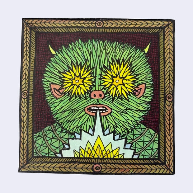 Illustration made with many lines, giving it the feel of a folk art woodcut on a square wood panel of a green fuzzy monster with star bursty yellow eyes, exclaiming a geometric pattern.