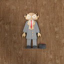 Wooden toy figure of a character with the head of a Big Boss Robot, wearing a gray suit with a red tie and a briefcase as an accessory.