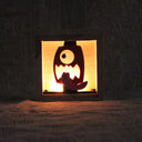 Wooden night light sculpture with a cut-out design of a face on a red lantern, with its tongue wildly out.