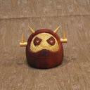 Wooden figure of a daruma figure with a golden face and head shaped like a Big Boss Robot.