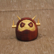 Wooden figure of a daruma figure with a golden face and head shaped like a Big Boss Robot.