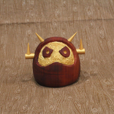 Wooden figure of a daruma figure with a golden face and head shaped like a Big Boss Robot.