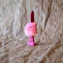 Whittled wooden sculpture of a pink Ocean Sunfish with a happy expression, standing on thin legs with pink shoes.