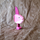 Whittled wooden sculpture of a pink Ocean Sunfish with a happy expression, standing on thin legs with pink shoes.