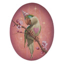 Painting on oval shaped panel of a green bird with a pink striped cone shaped party hat. It has a pink heart on its chest and is perched on a branch with blooming spring blossoms.