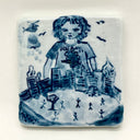 Blue drawing on a white ceramic tile of a girl wearing a t-shirt that reads "Destroy!" and standing over a much smaller city that is up in flames with small stick figures running around it.